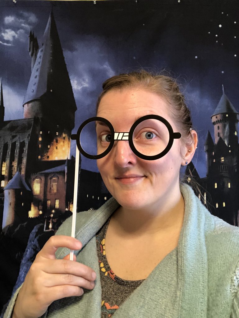 Me wearing Harry Potter-style glasses, standing in front of a backdrop of Hogwarts at night
